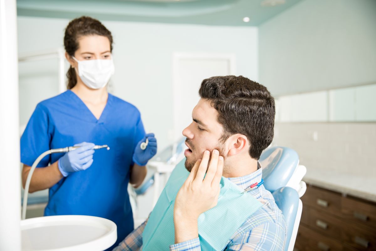 Man with a loose, painful tooth being assessed by a dental hygienist