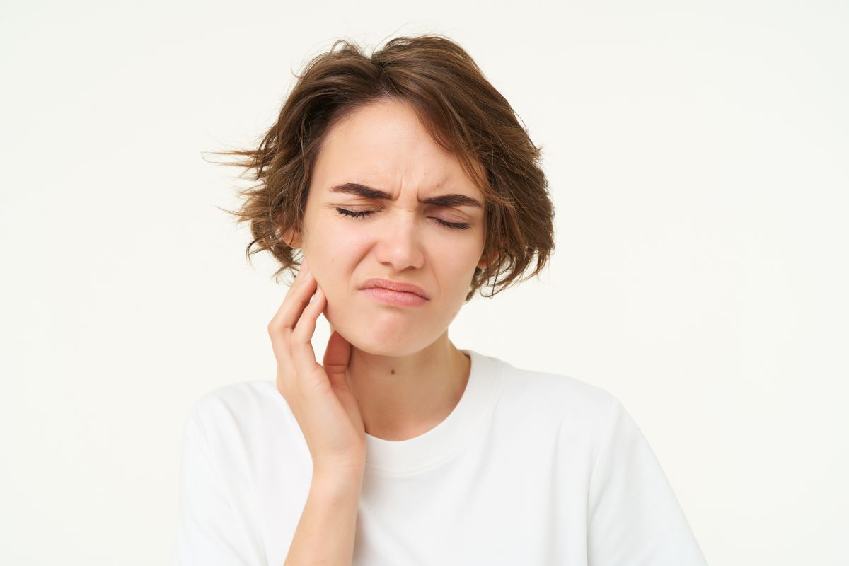 Woman wincing from facial swelling caused by a dental infection