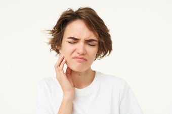Woman wincing from facial swelling caused by a dental infection