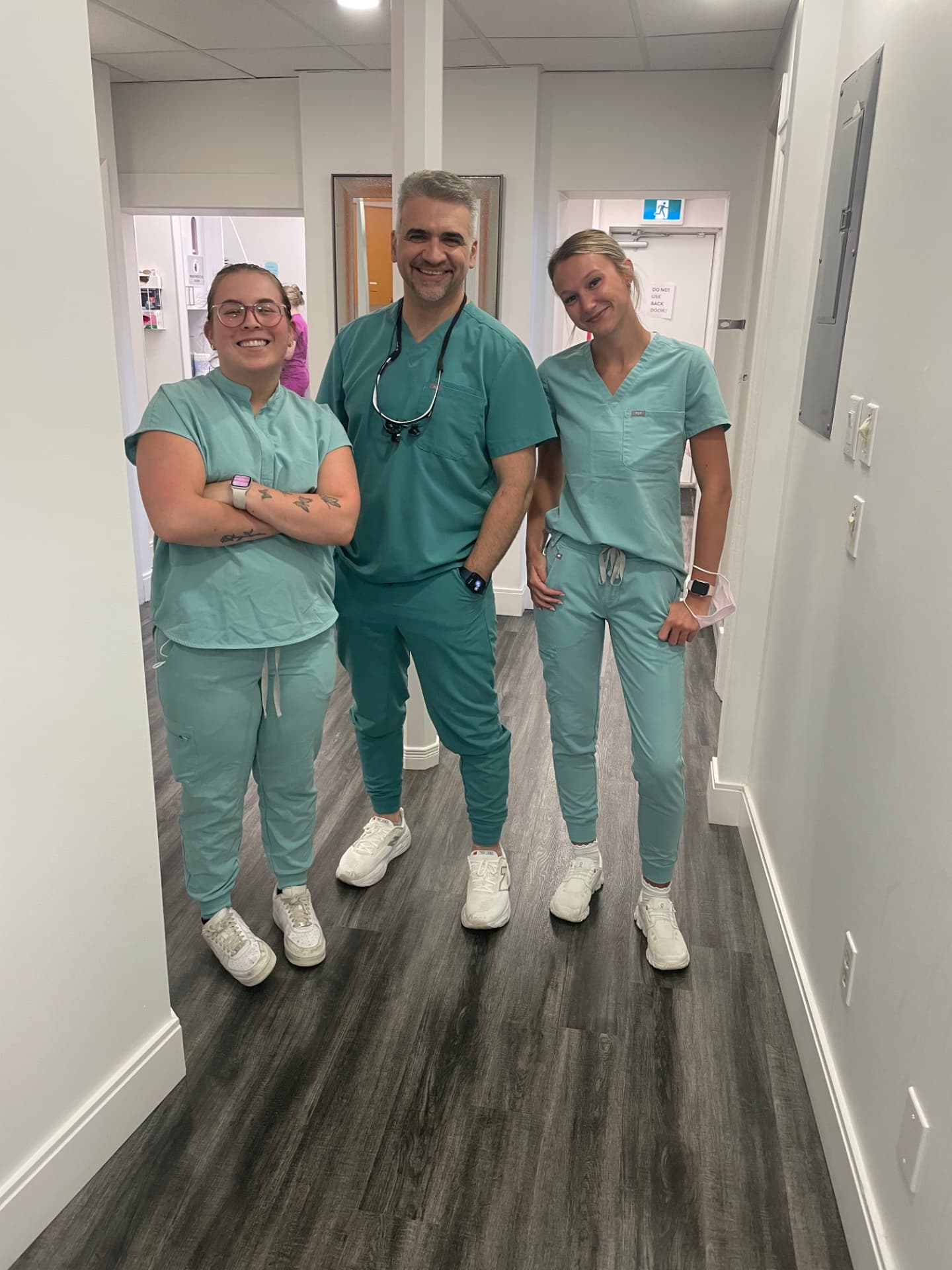 Three Welland Dental Centre clinicians in teal scrubs in the clinic hallway