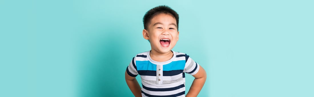Happy young boy in a striped shirt laughing and showing his healthy baby teeth