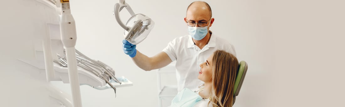 Oral Cancer Screening in Welland, ON | Welland Dental Centre Dentist adjusting the overhead light before examining a patient in the dental chair